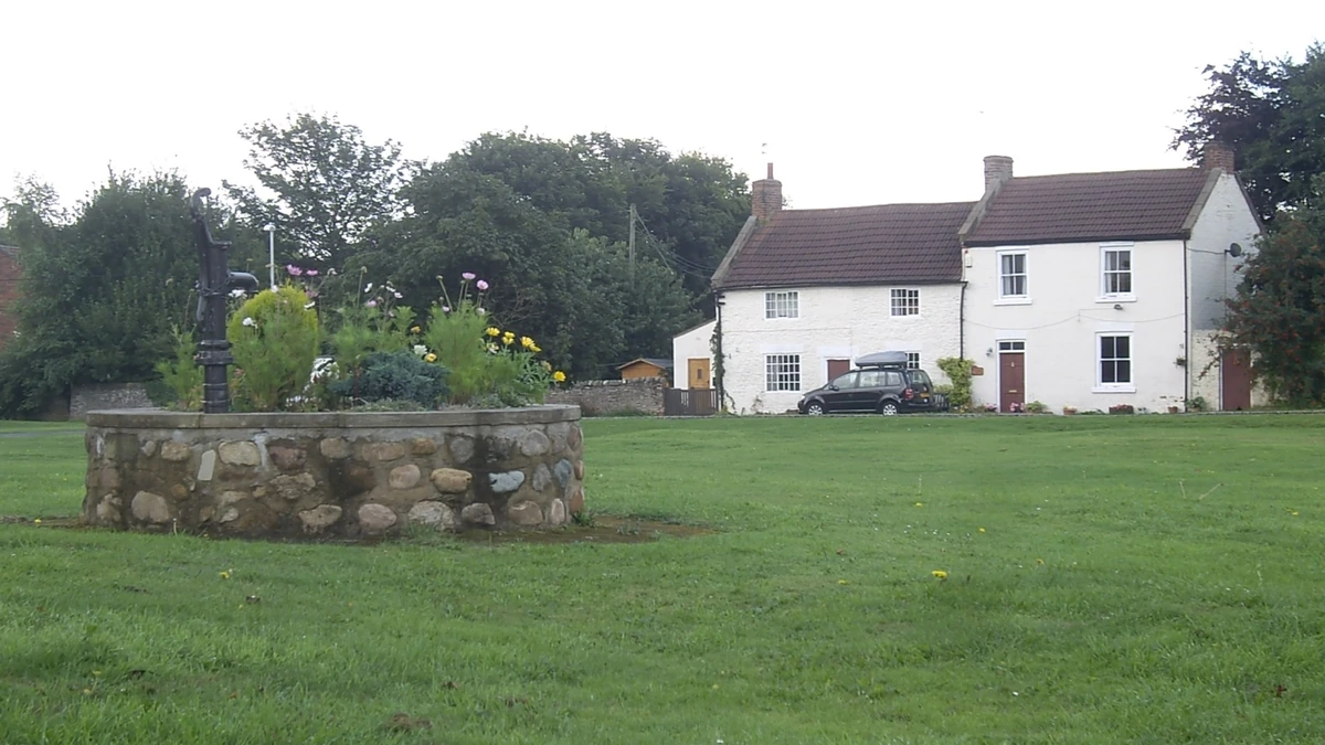 Illustrative stone water well in the garden of a rural home