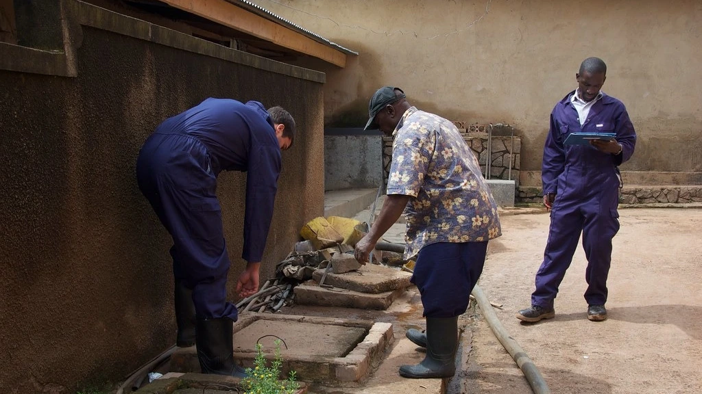 Workers opening a residential septic-tank access point for inspection