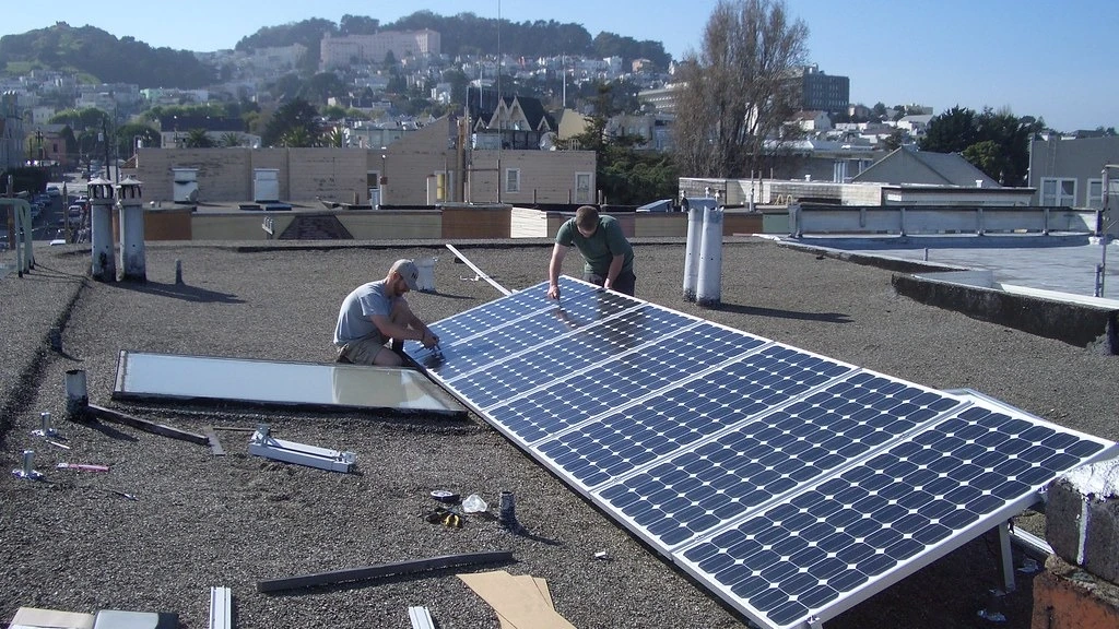 Solar installers positioning photovoltaic panels on a residential roof